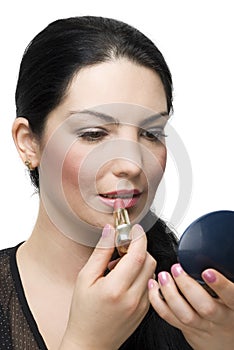 Brunette female applying lipstick in mirror