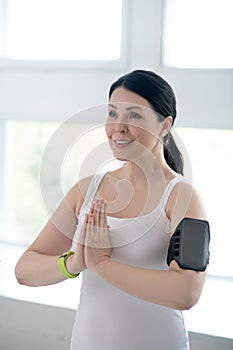 Brunette female performing namaste, pressing hands together, wearing pulsometer