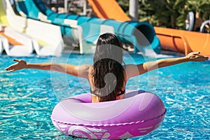 Brunette female in rubber ring in the swimming pool