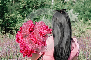 Brunette in a field with a bouquet of burgundy peonies