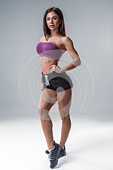 Brunette fitness girl in sport wear with perfect body in the studio posing before training set. Big Booty