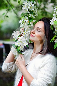 Brunette in flowers. The girl hugs a large bouquet of white flowers and smiles with her eyes closed. A young woman in flowers with
