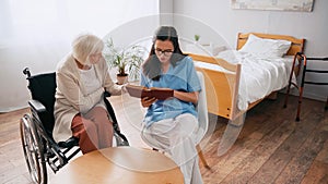 brunette geriatrician reading book to aged