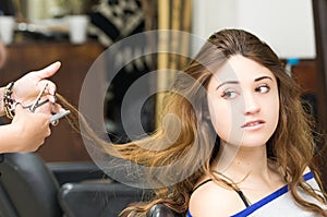 Brunette getting hair done by stylist hands while