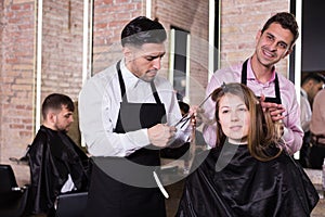 Brunette getting haircutting from two hairstylists