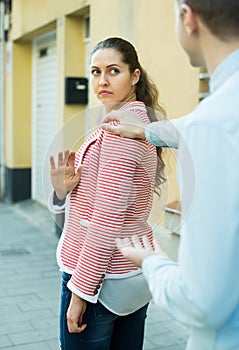 Brunette girl asking man to stop bothering her outdoors