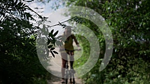 Brunette girl with a backpack rides a bicycle along a path of wooden flooring in a park on the shores of the Gulf of