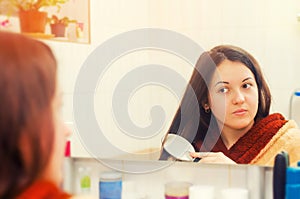 Brunette girl combing her hair looking in the mirror concept of beauty