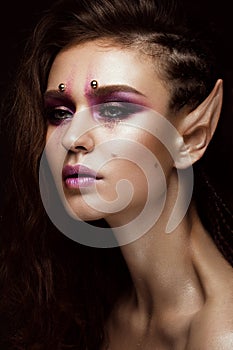 Brunette girl with a creative hairstyle braids, art make-up and the elf`s ears. Beauty face.