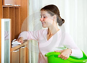 Brunette girl dusting furniture at home