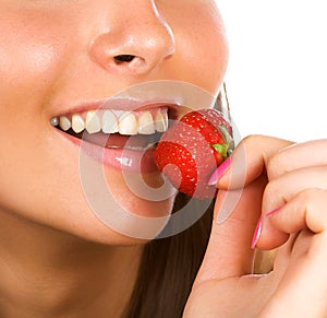 Brunette girl eating a strawberry