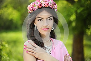 Brunette girl with flower chaplet in green filed wearing in pink