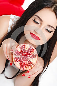 Brunette girl with garnet fruit in studio