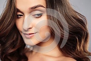Brunette girl with healthy curly hair and natural make up . Beautiful model woman with wavy hairstyle