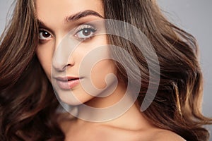 Brunette girl with healthy curly hair and natural make up . Beautiful model woman with wavy hairstyle