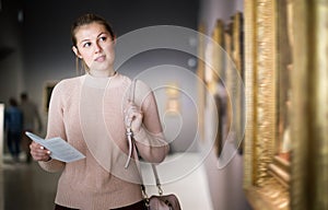 Brunette girl holding guide book in museum