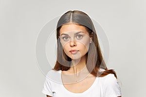 Brunette girl in a light T-shirt looks forward model close-up