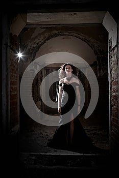 A brunette girl with long hair in an evening dress in a vintage Gothic castle. A woman who looks like an evil witch or