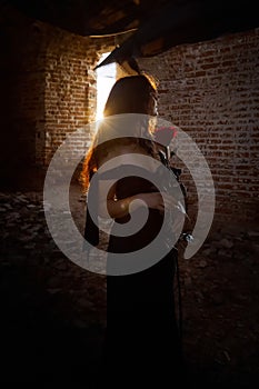 A brunette girl with long hair in an evening dress in a vintage Gothic castle. A woman who looks like an evil witch or