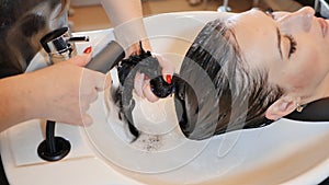 A brunette girl with long hair visits a beauty salon. Hair washing.
