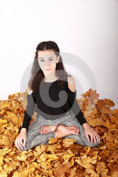 Brunette girl lying in lotus yoga pose on autumn leaves