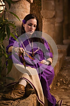Brunette girl in a medieval suit in a Agia Napa Medieval Monastery