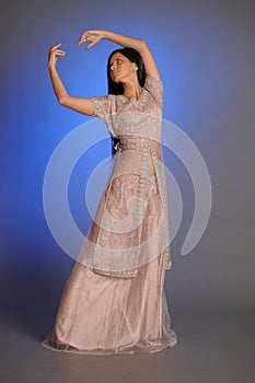 Brunette girl in oriental dress on a blue background in the studio