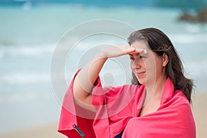 brunette girl in a pink towel on the beach