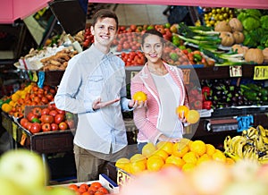 Brunette girl and smiling boyfriend buying citruses