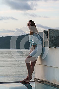 brunette girl stands at edge of villa pool overlooking Indian Ocean