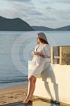 brunette girl stands at edge of villa pool overlooking Indian Ocean