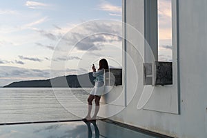 brunette girl stands at edge of villa pool overlooking Indian Ocean