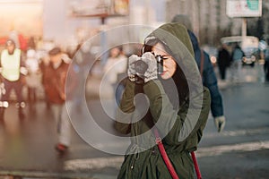 Brunette girl taking retro camera and focusing on somebody