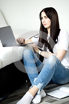 Brunette girl using laptop and smartphone at cozy home interior. Technology and communication concept