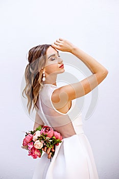 Brunette girl in a wedding dress. Bride in a white dress with a bouquet in her hands. Makeup. photo