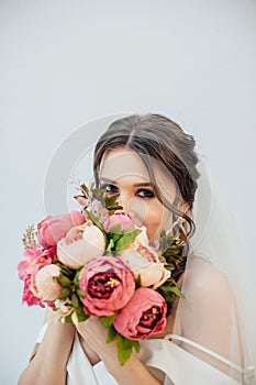 Brunette girl in a wedding dress. Bride in a white dress with a bouquet in her hands. Makeup. photo