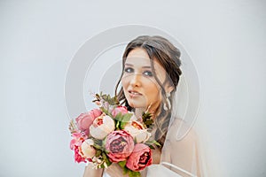 Brunette girl in a wedding dress. Bride in a white dress with a bouquet in her hands. Makeup. photo