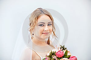 Brunette girl in a wedding dress. Bride in a white dress with a bouquet in her hands. Makeup. photo