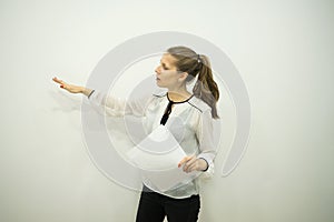 Brunette girl on a white background says and points to the wall with her right hand