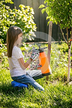 Brunette girl working in garden with fertilizing spray