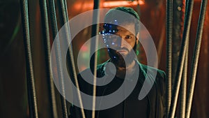 Brunette guy in Cyberpunk style with a headset stands behind black hanging rods