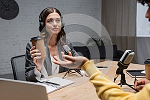 brunette interviewer in headphones holding paper