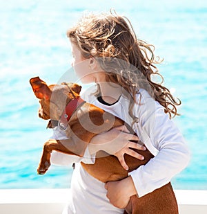 Brunette kid girl with dog on the sea