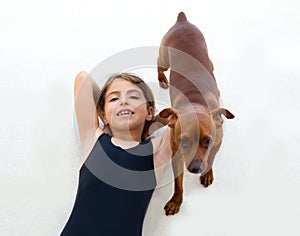Brunette kid girl in swimsuit playing with dog
