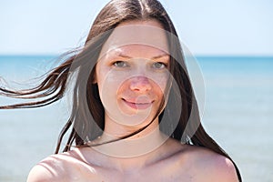 Brunette with long hair portrait. The sea in the background.