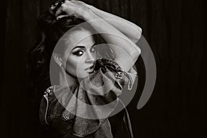 A brunette with long hair poses in the studio sitting on the floor on a black background.Black and white photo