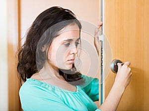 Brunette looking at broken lock of door