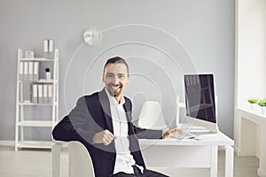 A brunette man in a black jacket sitting at the table works with papers in the office.