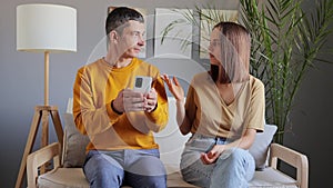 Brunette man using mobile phone browsing internet checking social network ignoring his wife offended woman with unhappy facial