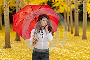 Brunette Model Enjoying A Fall Day In Fall Foliage With A Red Umbrella